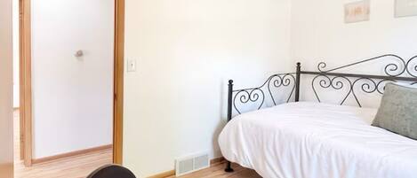 A bedroom with a bed, a desk, and a chair.