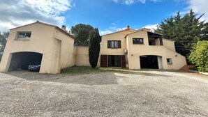 Una casa de dues plantes amb un camí de grava i un cotxe al camí.