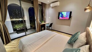A modern hotel room with a large bed, a TV, and a balcony with curtains. - River View Hotel (Ho Chi Minh City)