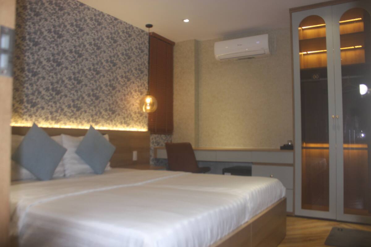 A hotel room with a large bed, a desk, and a wardrobe with a mirror.