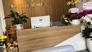 A hotel reception desk with clocks displaying different time zones, a VSP logo, and a wooden backdrop with city names. - River View Hotel (Ho Chi Minh City)