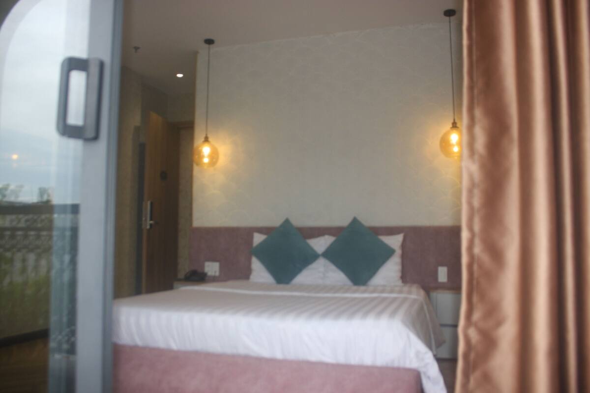 A hotel room with a bed, two wall-mounted lights, and a curtain.