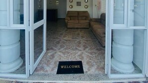 An entrance with a welcome mat, a brown sofa, and a tiled floor. - Hotel Boutique DL  (Cartagena)