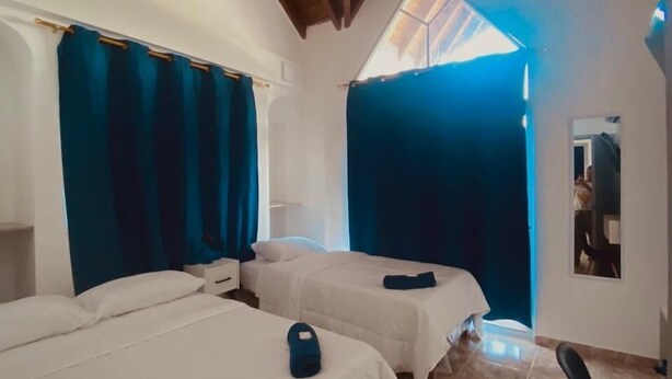 A room with two beds, a chair, and a skylight. - Hotel Boutique DL  (Cartagena)