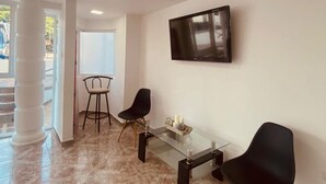 A modern dining area with a glass table, two black chairs, and a mounted TV. - Hotel Boutique DL  (Cartagena)