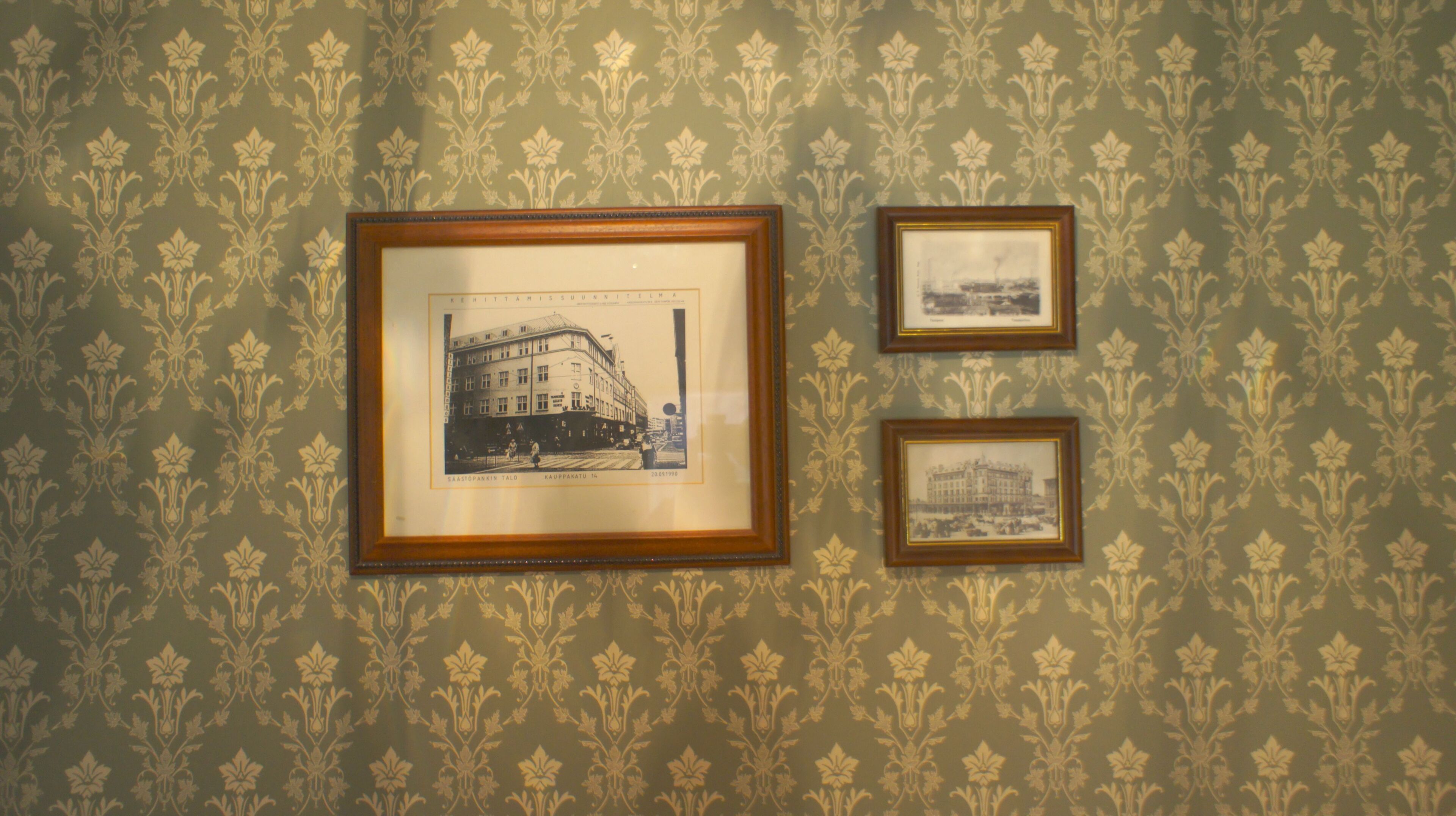 Tres fotografías enmarcadas en una pared con papel tapiz estampado.
