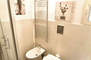A bathroom with a glass shower enclosure, a white sink, and a towel rack. - Green Chiaia two (Napoli)