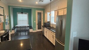 A modern kitchen with a black countertop, white cabinets, and a stainless steel refrigerator.