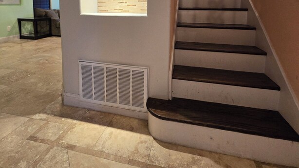 A staircase with a wooden handrail and a wall with a built-in shelf.