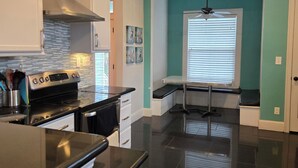 A modern kitchen with a black countertop, stainless steel appliances, and a teal accent wall.