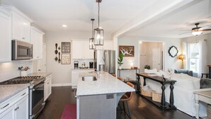 A modern kitchen with white cabinetry, stainless steel appliances, and a central island.
