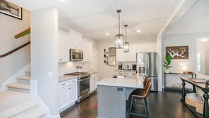 A modern kitchen with white cabinets, stainless steel appliances, and a central island with bar stools.
