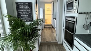 A narrow hallway with white cabinetry, a potted plant, and a sign listing local destinations.