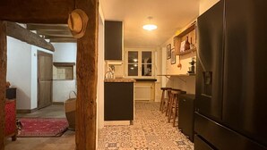 A compact kitchen with a black refrigerator, a small island, and a patterned tile floor.