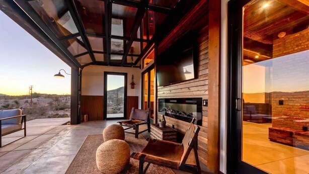 Un interior moderno con chimenea, zona de estar y ventanas amplias con vistas a un paisaje desértico.