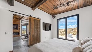 Un dormitorio con una cama grande, televisión y vistas al paisaje desértico.