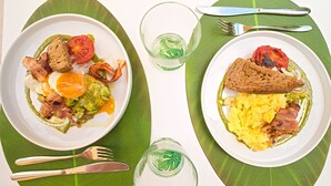 Two plates of breakfast with toast, eggs, and bacon on a table with green placemats. - B&B CASA GIOVANNA (Isola del Giglio)