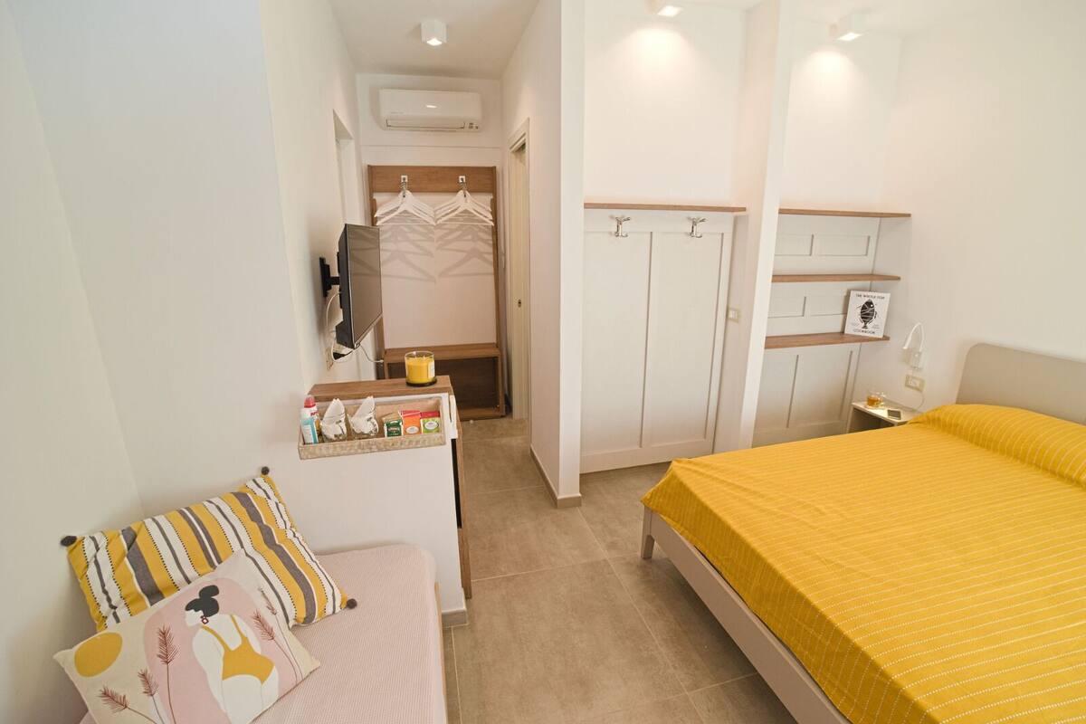 Ein Schlafzimmer mit Bett, Nachttisch, Kommode, Spiegel und Kleiderschrank.