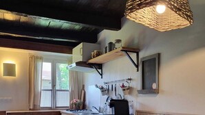 Una cucina accogliente con mobili in legno, un lampadario e una finestra con tende.