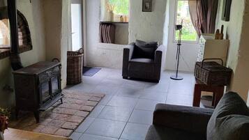 Un salon chaleureux avec une cheminée, un canapé, un fauteuil et une table.