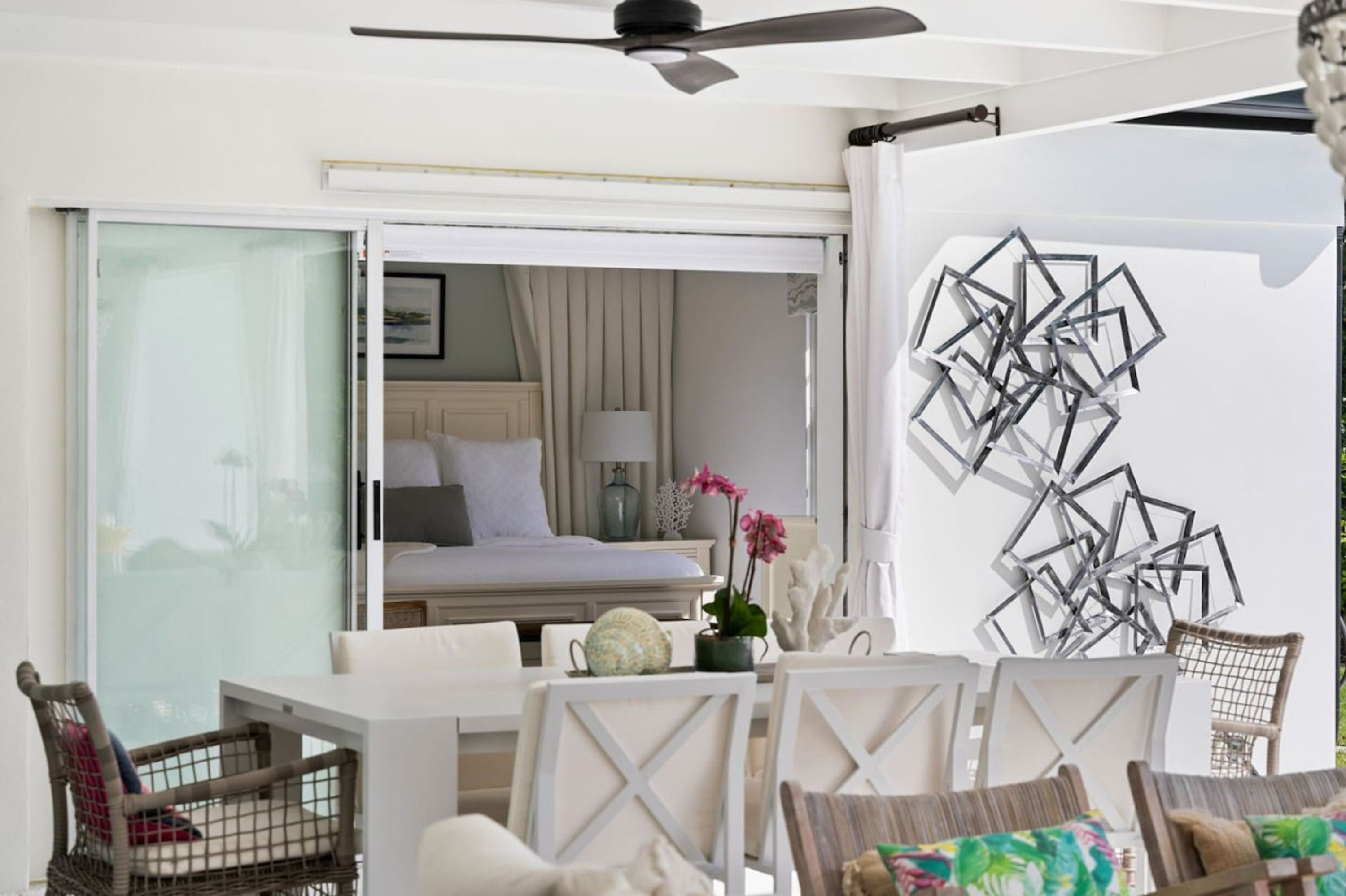 A hotel room with a bed, a desk, chairs, and a decorative wall piece.