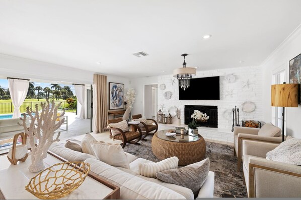 A spacious living room with a fireplace, comfortable seating, and a view of the outdoors.