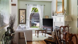 Un salon spacieux doté d’une grande télévision, de sièges confortables, d’une cheminée et offrant une vue sur l’extérieur.