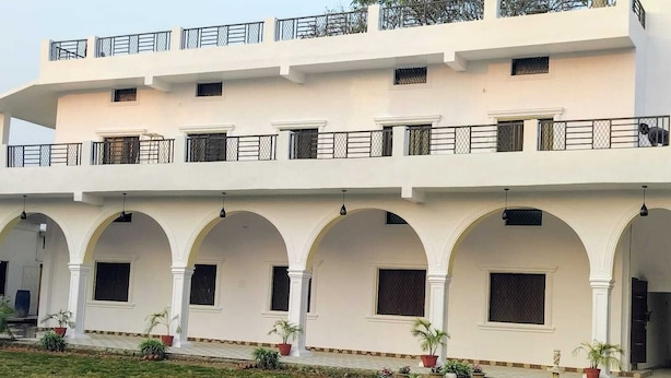 Un edificio de varios pisos con fachada blanca, varios balcones y un corredor cubierto con arcos.
