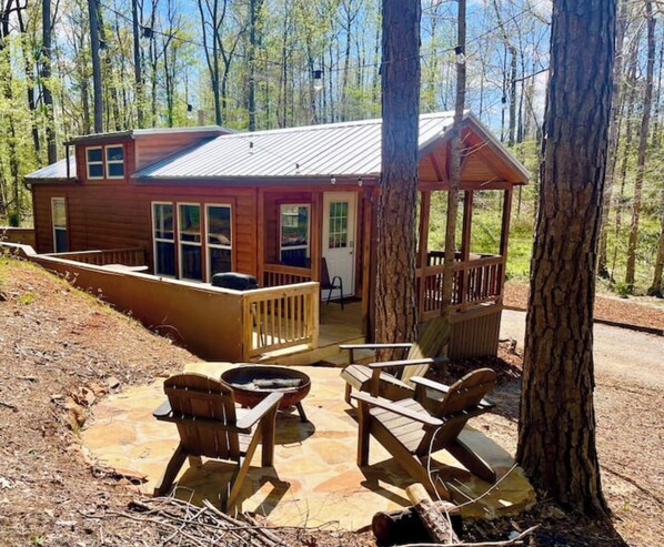 A cabin with a porch, outdoor seating, and a fire pit.