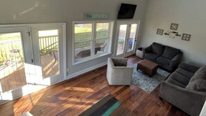 A spacious living room with a ceiling fan, a large window, and a view of a deck. - Waverly Creek Retreat-kayaks/fire pit/pet friendly (Jackson's Gap)