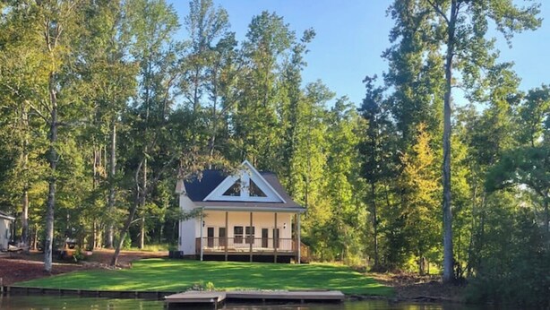 A house with a gabled roof, surrounded by a pond and trees. - Waverly Creek Retreat-kayaks/fire pit/pet friendly (Jackson's Gap)