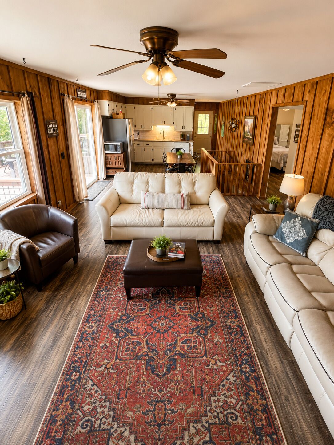 A spacious living room with a large ceiling fan, a fireplace, and a view of the kitchen.