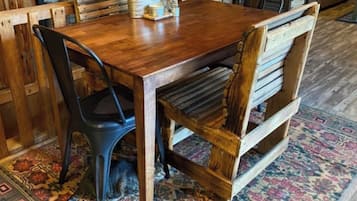 A wooden dining table with chairs, a patterned rug, and a potted plant.