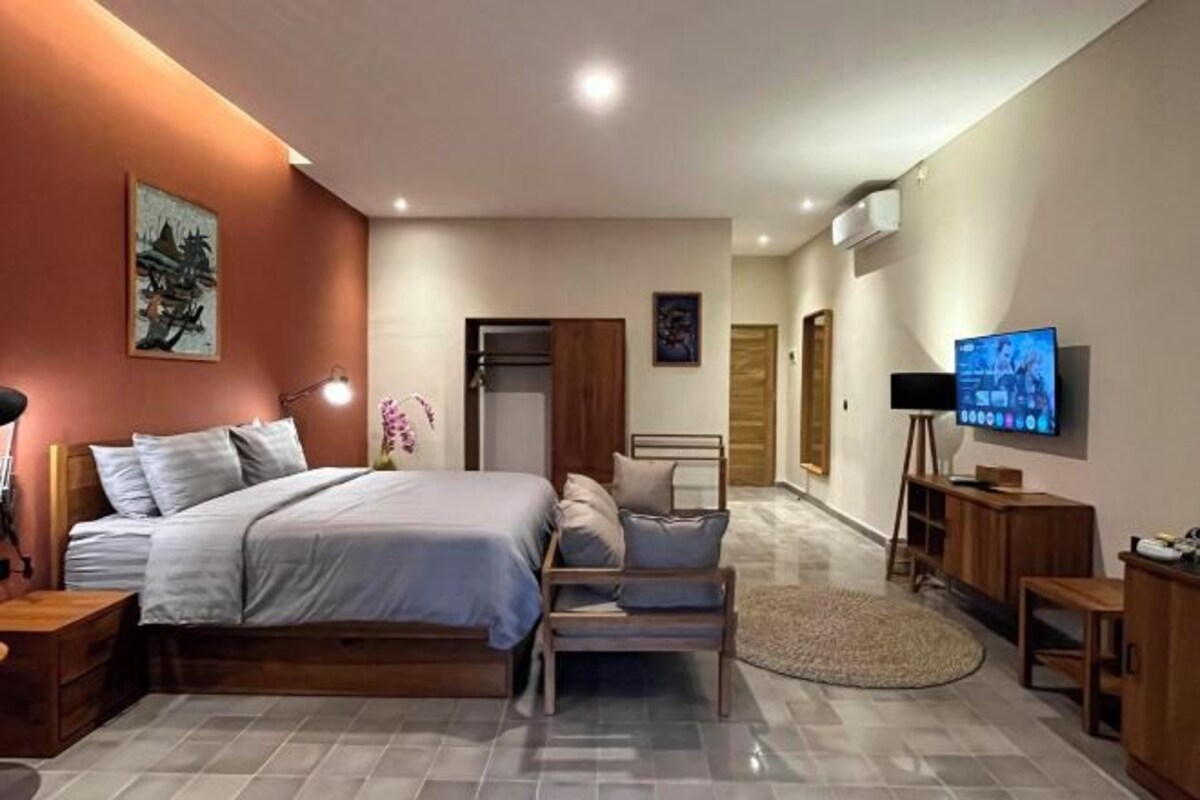 Un dormitorio moderno con cama, mesitas de noche, televisor y un banco de madera.