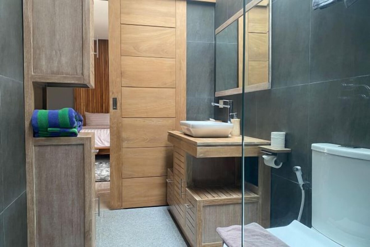 A modern bathroom with a wooden vanity, a glass shower enclosure, and a visible toilet.