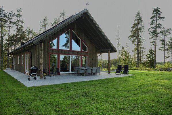 A modern wooden cabin with large windows and a patio area.