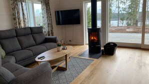 A modern living room with a sofa, coffee table, and a fireplace. - Berget Lövanäs 2, Newly built modern house in secluded location with own jetty and boat (Korsberga)