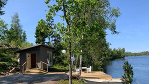 A cabin with a dock and a small boat, surrounded by trees and a lake. - Berget Lövanäs 2, Newly built modern house in secluded location with own jetty and boat (Korsberga)