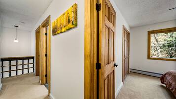 A hallway with wooden doors, a painting, and a window with a view of trees.