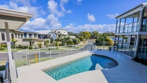Ein modernes Gebäude mit Swimmingpool, überdachtem Gang und Blick auf die Umgebung.