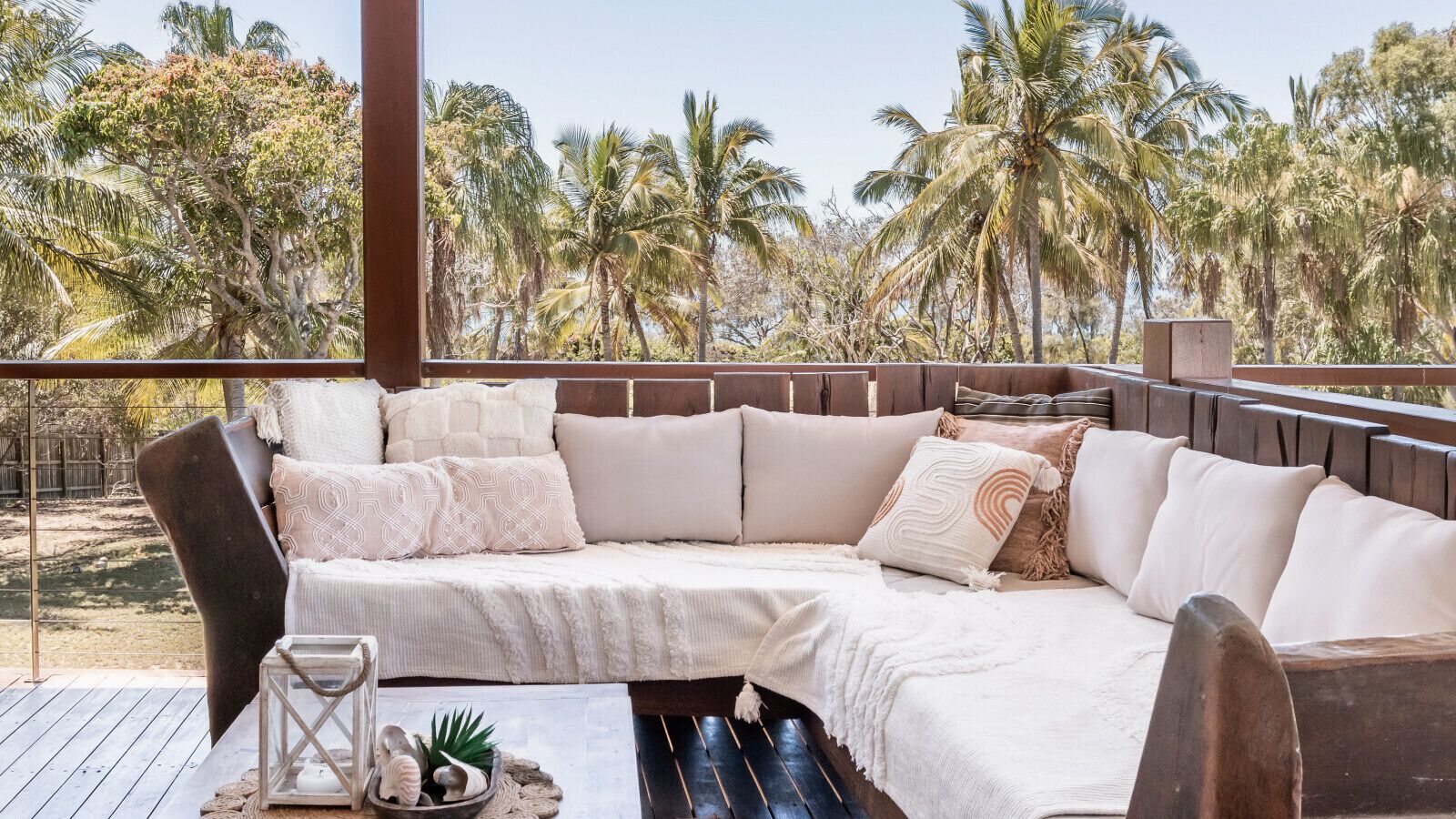 A cozy outdoor seating area with a cushioned sofa, a small table, and a decorative plant.