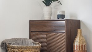 A corner of a room with a wooden cabinet, a woven basket, a wicker vase, and a potted plant.