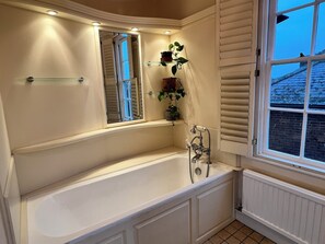 A bathroom with a freestanding bathtub, a window with blinds, and a potted plant on a shelf. - Stylish Georgian Townhouse in Rye Citadel (Rye)
