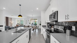 A modern kitchen with white cabinetry, stainless steel appliances, and a central island. - Hogwarts & Mickey! Marvel Gameroom! Resort Near Disney (Davenport)