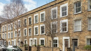 A row of brick townhouses with white-framed windows, a tree in the foreground, and cars parked on the street. - Modern 2 Bedroom Townhouse Flat in King's Cross (London)