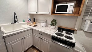 Una cocina moderna con armarios blancos, microondas integrado, estufa y lavamanos.