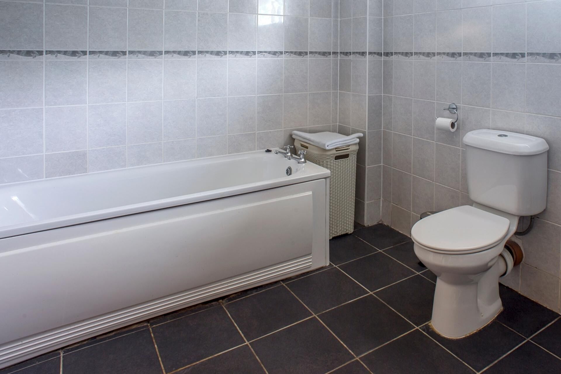Une salle de bain avec une baignoire, des toilettes et un panier en osier.