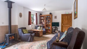 A cozy living room with a fireplace, a bookshelf, a sofa, and a wooden door. - Accessible Friendly Farm Stay (Mayfield)