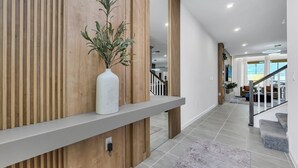 En modern inredning med en väggpanel i trä, en vit vas med gröna växter och en trappa som leder till ett annat våningsplan.