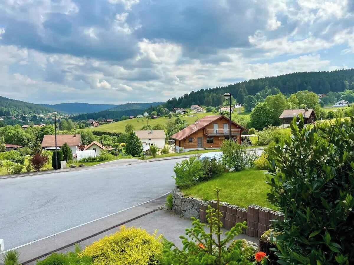Eine Wohnstraße mit Häusern, einer Holzhütte und blauem Himmel.